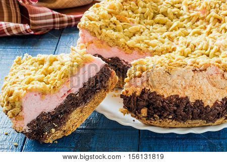 Baking in multicooker. Homemade festive multilayer cake with jam chocolate marshmallows streusel and a cup of tea on a blue wooden background. Selective focus