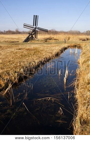 Paaltjasker windmill in a harvest reedfield in nature reserve and national park Weerribben-Wieden in the Netherlands