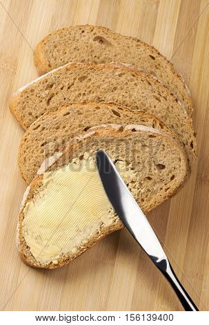 Close up a knife spreading butter on bread