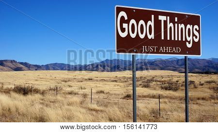 Good Things Just Ahead brown road sign with blue sky and wilderness