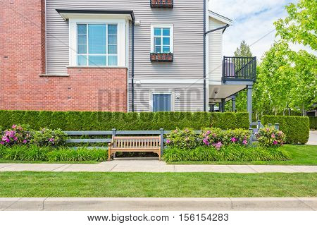 Fragment of the condo side with the bench, front yard, side walk.