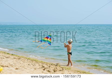Little boy resting and playing on the beach with a kite