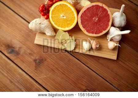 traditional medicine, cooking, food and ethnoscience concept - citrus fruits, ginger and garlic on wooden background