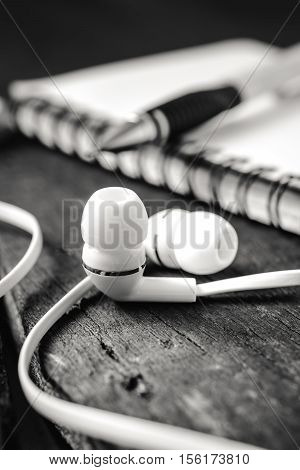White Headphones, Smartphone With Notebook On Wood Table Background Vintage Color.