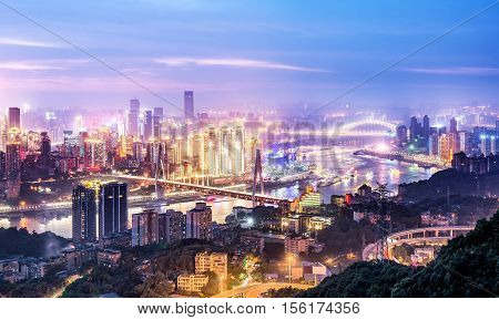 cityscape and skyline of downtown near water of chongqing at night