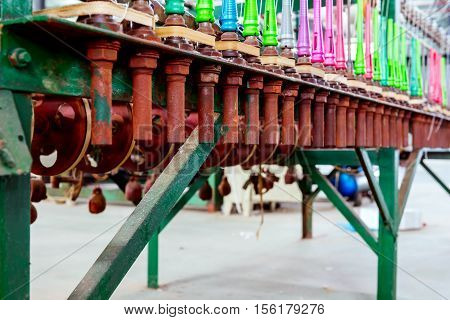 A row of textile looms weaving cotton yarn in a textile mill.