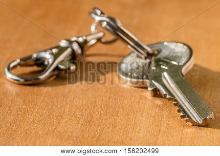House key on a chain on a wooden background. Soft focus shallow DOF