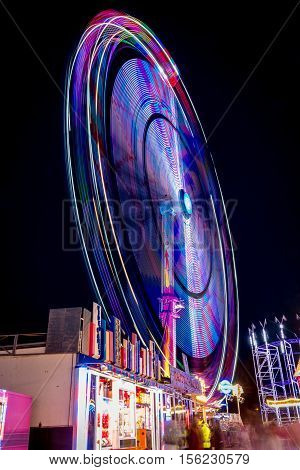 Ferris wheel shoot at night while rotating at the fair in Antwerpen Belgium. The lights draw a colourful circle.