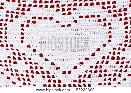 White lace doily with heart on red background close up