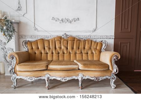 Living room with antique stylish beige sofa on luxury white wall design bas-relief stucco mouldings roccoco elements. Black and white photo