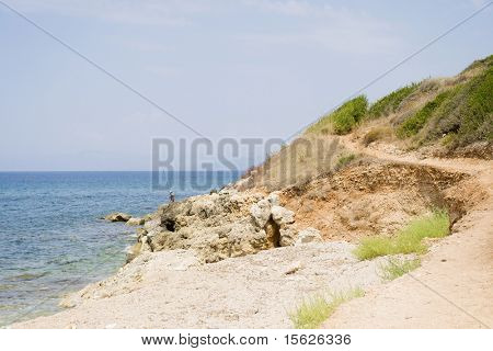 Grecque côte sauvage avec les roches et le pêcheur