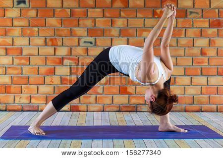 woman yoga exercices fitness sport training and lifestyle concept - smiling woman stretching leg on mat in gym