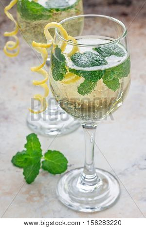 Spritzer cocktail with white wine mint and ice decorated with spiral lemon zest vertical