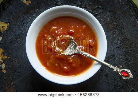 Adjika (Tomato sauce with peppers and spices) in a bowl on a black background