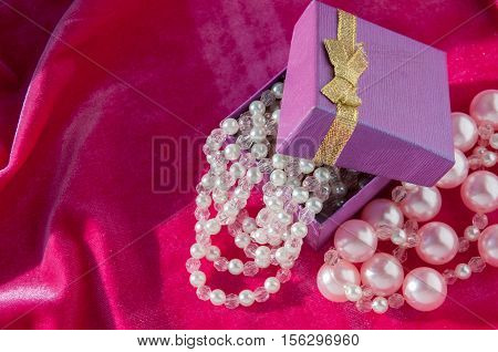 Gift with pink pearl strings on a crimson velvet