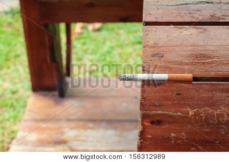 Cigarette burn selective focus on a wooden table at hazard Health
