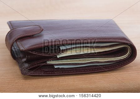 brown men's wallet with money on a wooden background