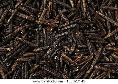 Black rice close-up background. Heap wild brown unpolished rice for vegetarians.