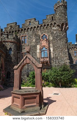Reichenstein Castle Rhine Valley Germany - UNESCO World Heritage - courtyard with stone well ancient wall with windows and carved turrets against the blue sky