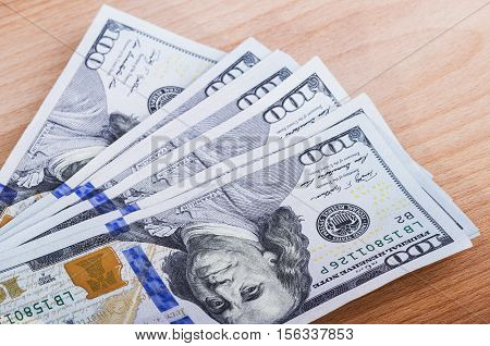 several hundred dollar bills on a wooden table