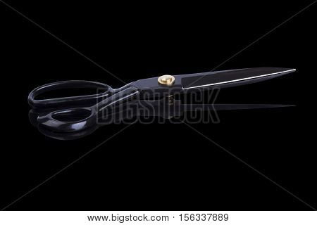 Large stainless steel tailor scissors on a black background