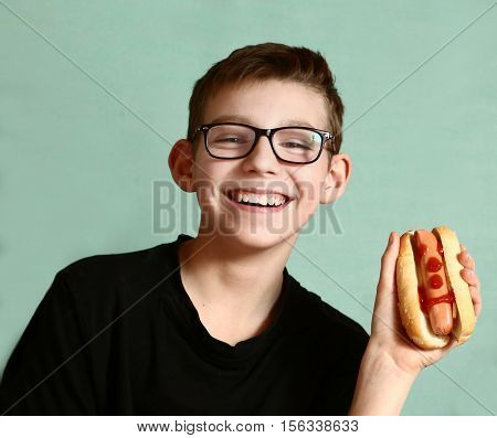 teen handsome boy in myopia glasses with hot dog happy smiling close up portrai