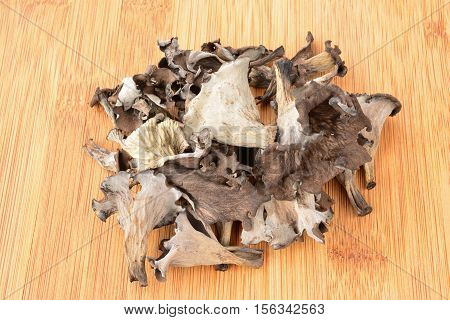 Pile of first class dried Horn of Plenty mushrooms on bamboo dark wooden chopping board
