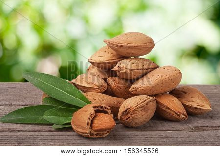 heap of almonds in their skins and peeled with leaf isolated on white background.