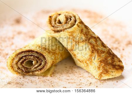 Crepe rolls filled with cinnamon and sugar photographed with natural light (Selective Focus Focus on the front side of the right roll)