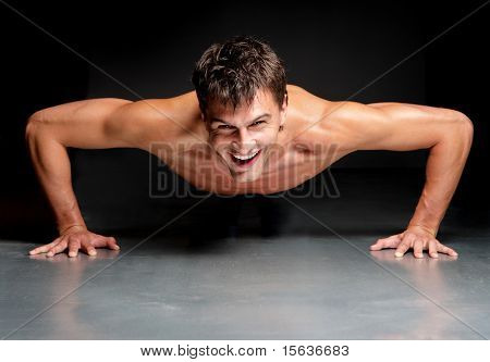 jovem macho fazendo física exersize sobre um fundo escuro