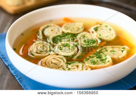 Traditional German Flaedlesuppe and Austrian Frittatensuppe based on consomme with rolls or stripes of pancake or crepe garnished with chives photographed with natural light (Selective Focus Focus in the middle of the soup)