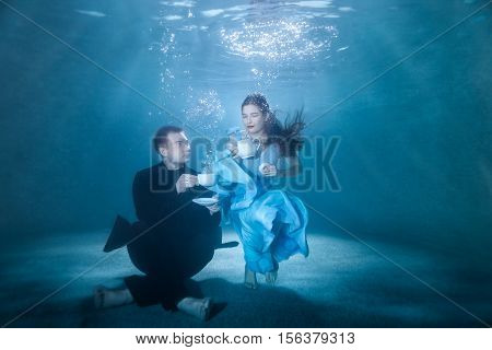 Man and woman on the bottom of the pool spend the tea ceremony.