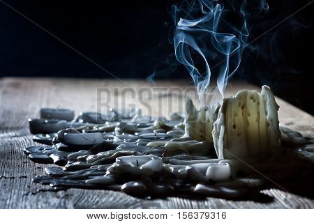 Blue smoke with candls on wooden shelf on black background