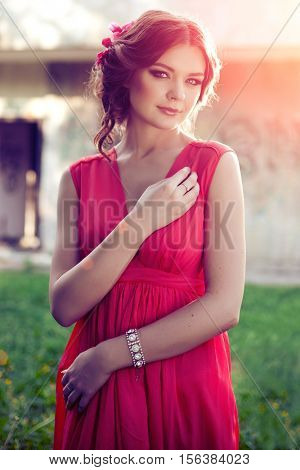 Beautiful girl on the nature in the park. Against the background of the summer lanshaft. Young romantic woman in the sunshine, sunset.