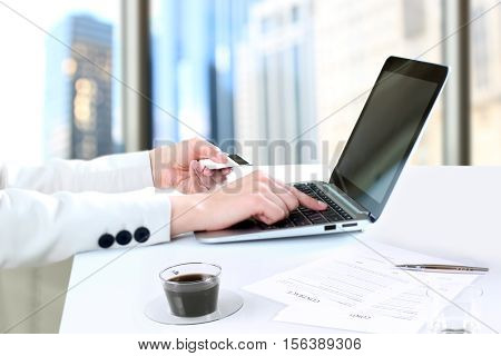 Business woman entering data of a credit card . On-line shopping on the internet using a laptop