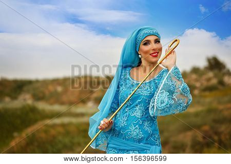 Oriental beauty Sa'idi dance. Nice girl wearing a national costume dancing shepherdess with shepherd's cane outdoors. Nomads.