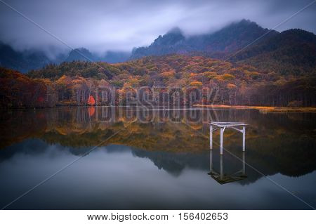 Amazing autumn lake scenery of Kagami Ike (Mirror Pond) in morning rainy day. Togakushi Mountain in background in Nagano, Japan.