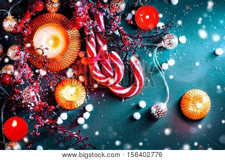 Christmas Holiday Background with Candy Cane, decorations, candles, garland and evergreens border over dark background table. Christmas and New year food. Christmas dinner, served table, decorations