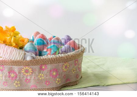 Basket of Hand Painted Easter Eggs with Daffodils on Table Horizontal with Copy Space & Bokeh