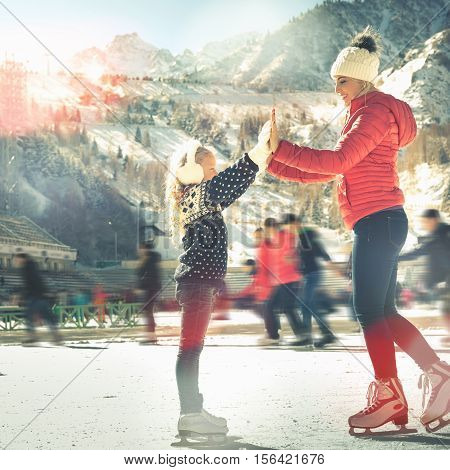 Happy family outdoor ice skating at rink. Mother and daughter has winter activities. Mom, kids. Medeo stadium. Almaty.