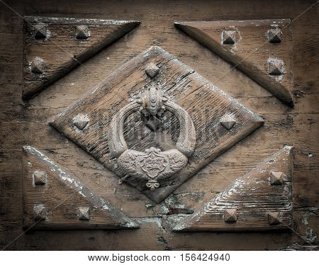 A large decorative vintage door handle on a wooden door