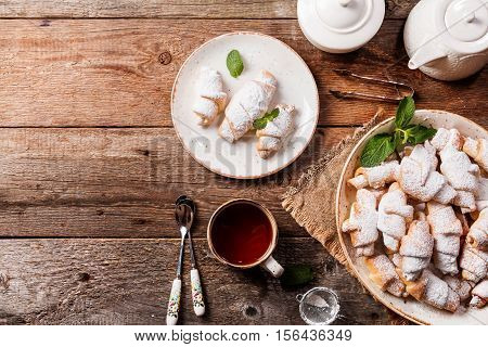 Rugelach with jam filling on plate with tea on wooden background, top view with copy space