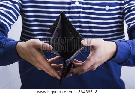 man holding an empty black leather wallet