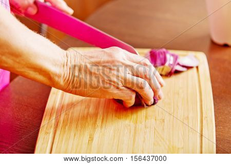 Woman cut red onion on cutting board