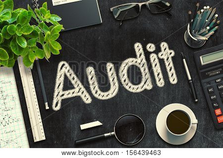 Black Chalkboard with Handwritten Business Concept - Audit - on Black Office Desk and Other Office Supplies Around. Top View. 3d Rendering. Toned Image.