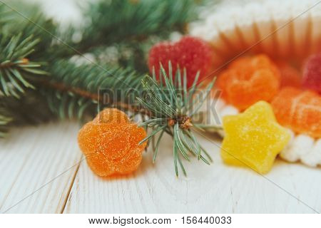 Christmas composition with fir branch and jujube candy in the knitted white hat.Orange sweet flower.
