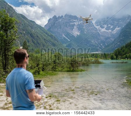 Man controls drone with mountains on background. Alps, Italy