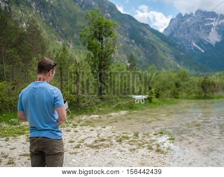 Man controls drone with mountains on background. Alps, Italy