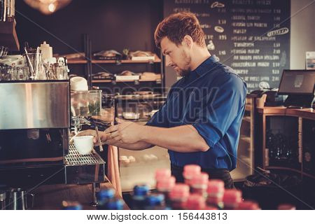 Handsome barista preparing cup of coffee for customer in coffee shop
