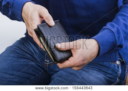 a man holding a black leather wallet with money